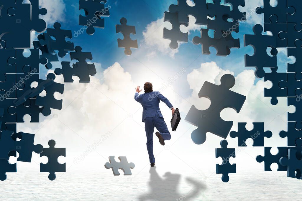 Businessman breaking the wall of jigsaw puzzle