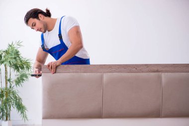 Genç erkek müteahhit eve mobilya kuruyor.