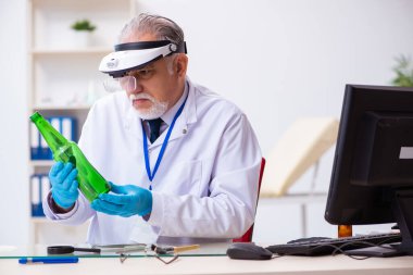 Kanıt için laboratuvarda çalışan yaşlı bir erkek kriminolog.