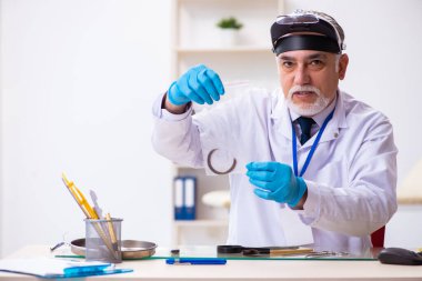 Kanıt için laboratuvarda çalışan yaşlı bir erkek kriminolog.