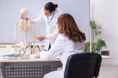 Genç erkek öğretmen doktor, iskelet ve kız öğrenci.