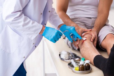 Yaralı adam ilk yardım konseptinde yaşlı doktoru ziyaret ediyor.
