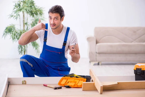 Junger männlicher Bauunternehmer installiert Möbel zu Hause — Stockfoto