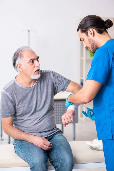 Junger Arzt und alter Patient im Erste-Hilfe-Konzept — Stockfoto