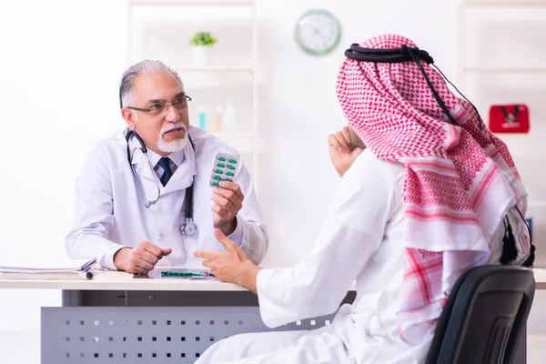 Young male arab visiting experienced male doctor — Stock Fotó