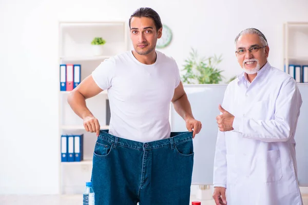 Doctor dietician and happy patient wearing large trousers — Stockfoto