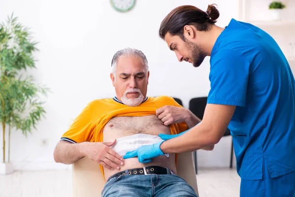 Alt mann besuch jung männlich doktor — Stockfoto