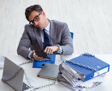 Ofis masasına zincirlenmiş meşgul bir çalışan.