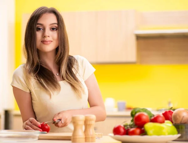 Jonge vrouw bereidt salade thuis in de keuken — Stockfoto