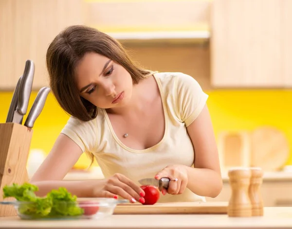 Jovem mulher preparando salada em casa na cozinha — Fotografia de Stock