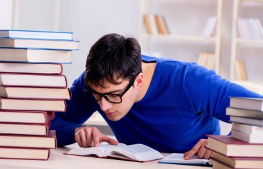 Erkek öğrenci üniversite kütüphanesinde sınava hazırlanıyor.