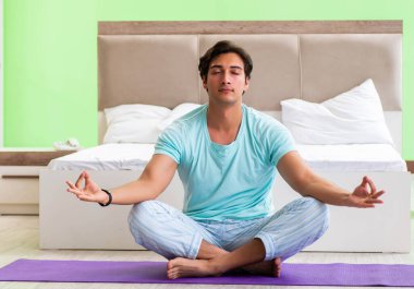 Pijamalı genç adam sabah egzersizi yapıyor.