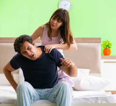 Yatak odasında kocasına masaj yapan bir kadın.