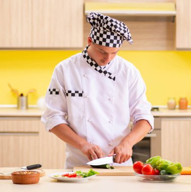 Genç profesyonel aşçı mutfakta salata hazırlıyor.