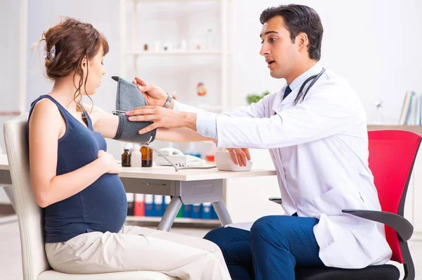 Young doctor checking pregnant womans blood pressure — Stock Photo, Image