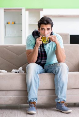 Evde hastalıktan muzdarip genç yakışıklı bir adam.