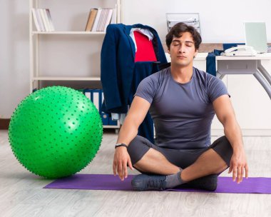 Ofiste egzersiz yapan genç bir erkek.