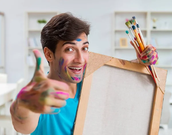 Молодой забавный художник работает над новой картиной в своей студии — стоковое фото