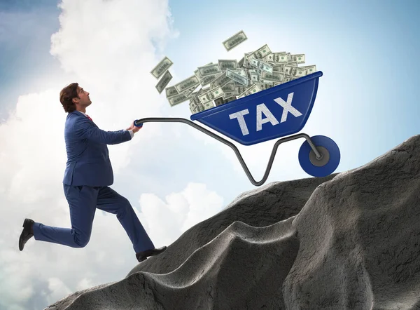 Бизнесмен толкает налоговую тачку в гору — стоковое фото