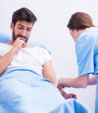 Kadın doktor erkek hastayı hastanede muayene ediyor.