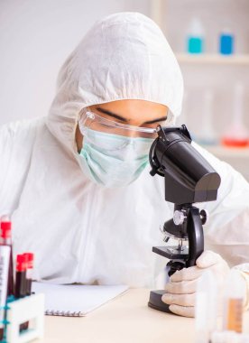 Genç yakışıklı laboratuvar asistanı hastanede kan örnekleri test ediyor.