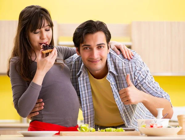 Man and pregnant woman preparing salad in kitchen — Stock Photo, Image