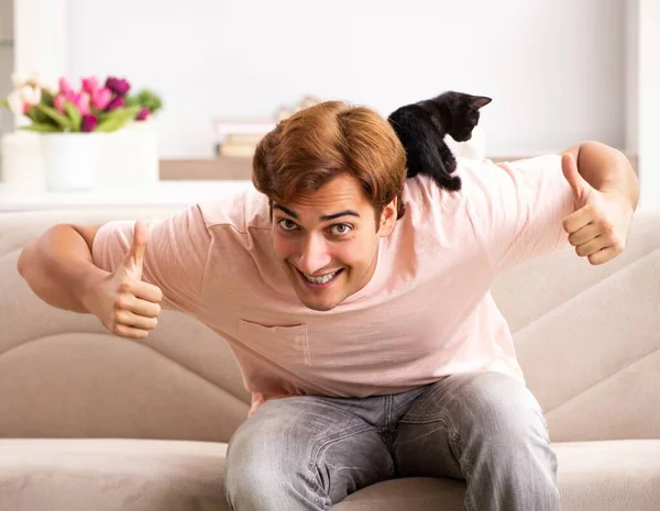 Молодой человек играет с котенком дома — стоковое фото
