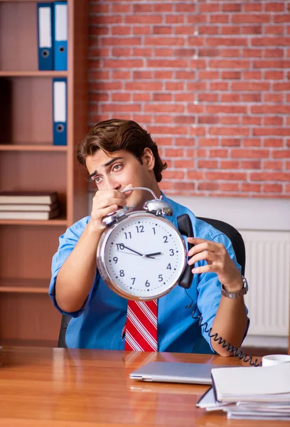 Ung anställd med överdrivet arbete sittande på kontoret — Stockfoto