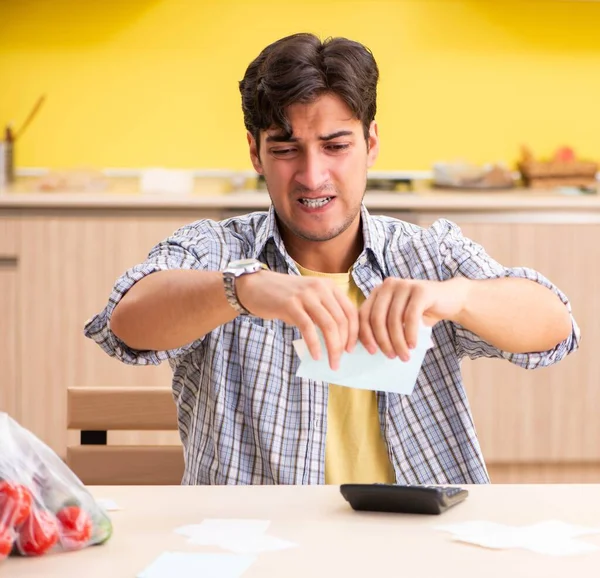 Jeune homme calcul des dépenses pour les légumes dans la cuisine — Photo