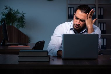 Gece ofiste çalışan genç bir erkek.