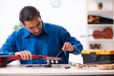 Gitarı tamir eden genç bir erkek tamirci.