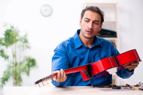 Mladý muž opravář opravuje kytaru — Stock fotografie