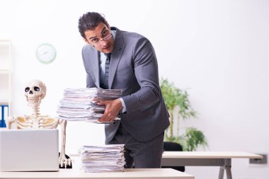 Genç erkek çalışan ve iskelet ofiste.