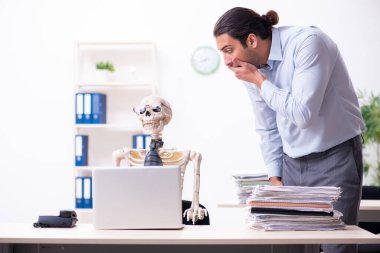 Genç erkek çalışan ve iskelet ofiste.