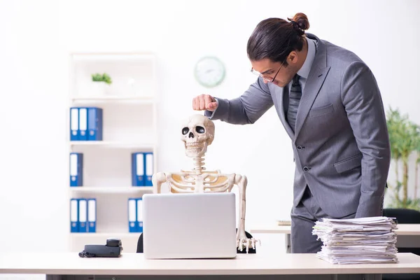 Joven empleado masculino y esqueleto en la oficina —  Fotos de Stock