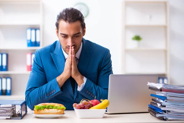 Jonge mannelijke werknemer ontbijten op de werkplek — Stockfoto