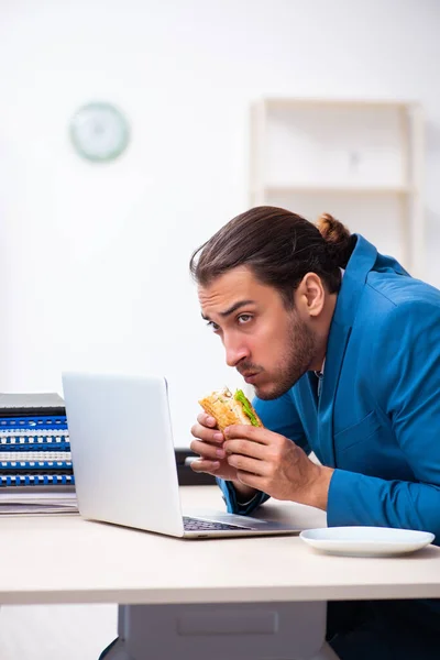 Joven empleado masculino desayunando en el lugar de trabajo —  Fotos de Stock