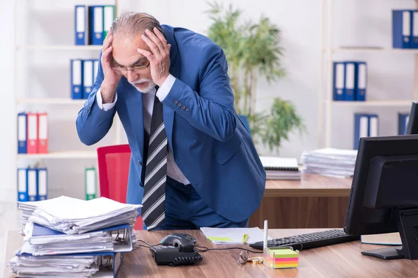 Velho empregado masculino e excesso de trabalho no escritório — Fotografia de Stock