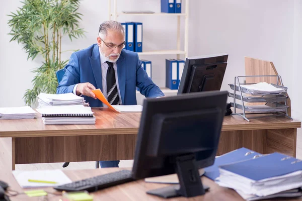 Gammal manlig anställd och överdrivet arbete på kontoret — Stockfoto