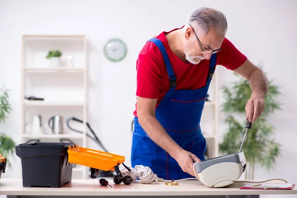 Antigo empreiteiro masculino reparando ar ar condicionado dentro de casa — Fotografia de Stock