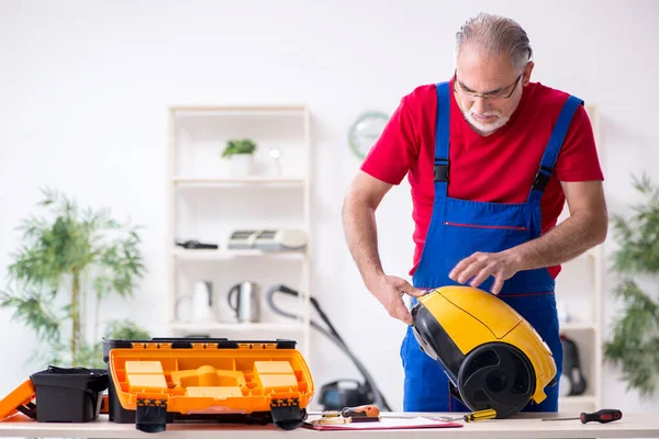 Evde elektrik süpürgesi tamir eden yaşlı bir erkek müteahhit. — Stok fotoğraf