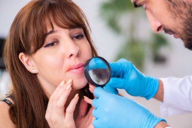 Genç bir kadın erkek doktor dermatoloğunu ziyaret ediyor.