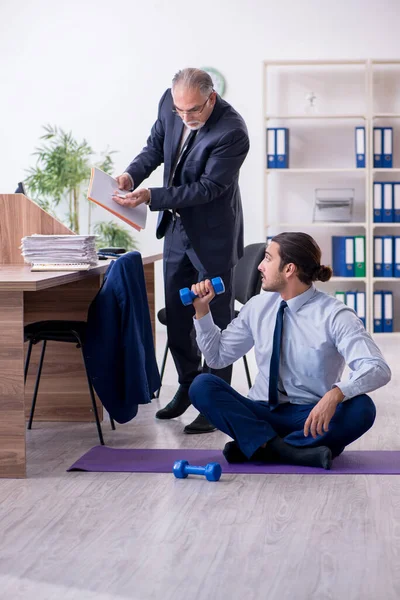 Dois funcionários fazendo exercícios físicos no local de trabalho — Fotografia de Stock