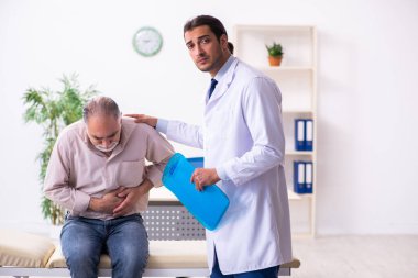 Yaşlı hasta genç erkek doktoru ziyaret ediyor.