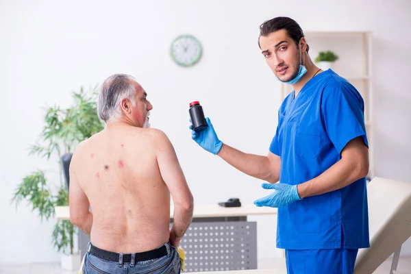 Starý muž návštěva mladý lékař dermatolog — Stock fotografie
