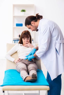 Yaralı genç kadın genç erkek doktoru ziyaret ediyor.