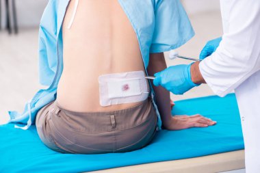 Yaralı genç kadın genç erkek doktoru ziyaret ediyor.