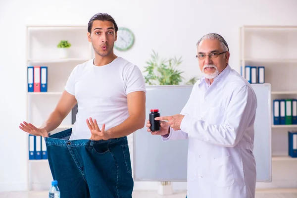 Doctor dietician and happy patient wearing large trousers — Stok fotoğraf