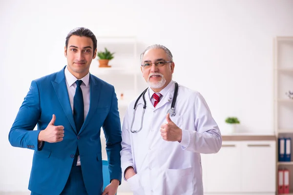 Jeune homme d'affaires rencontre avec un vieux médecin — Photo