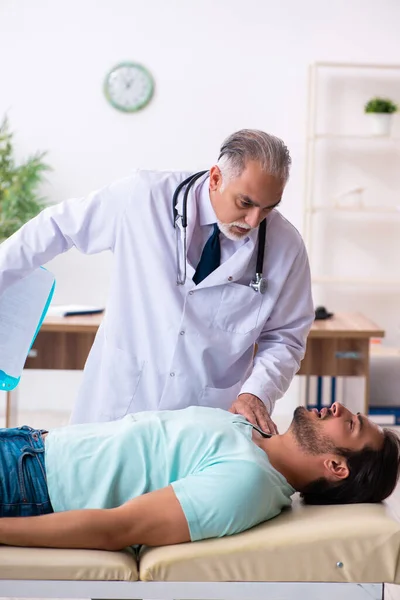 Joven herido visitando al viejo doctor — Foto de Stock